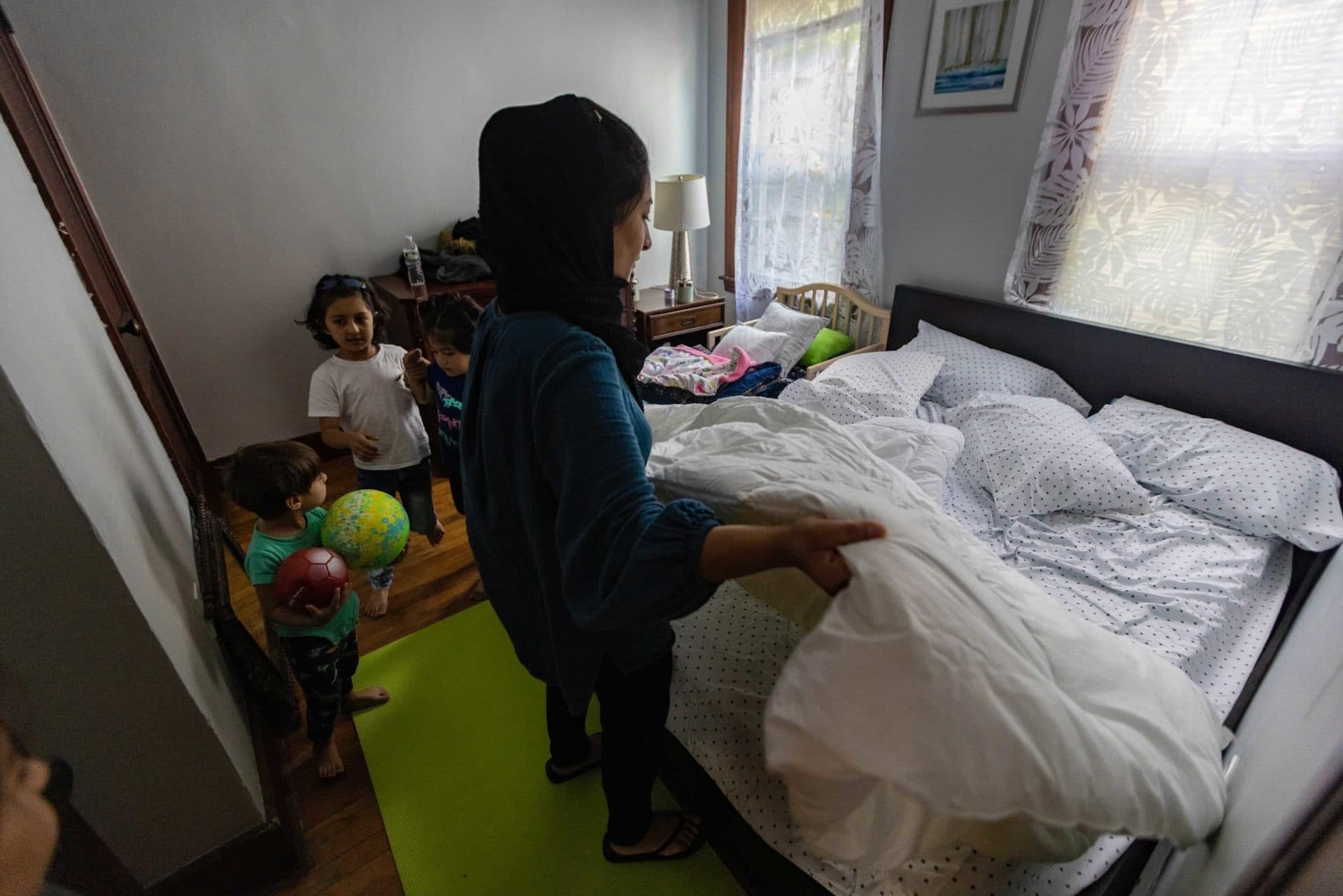 Shaista Atayi makes up the bed in their bedroom in their new apartment in Worcester. (Jesse Costa/WBUR)