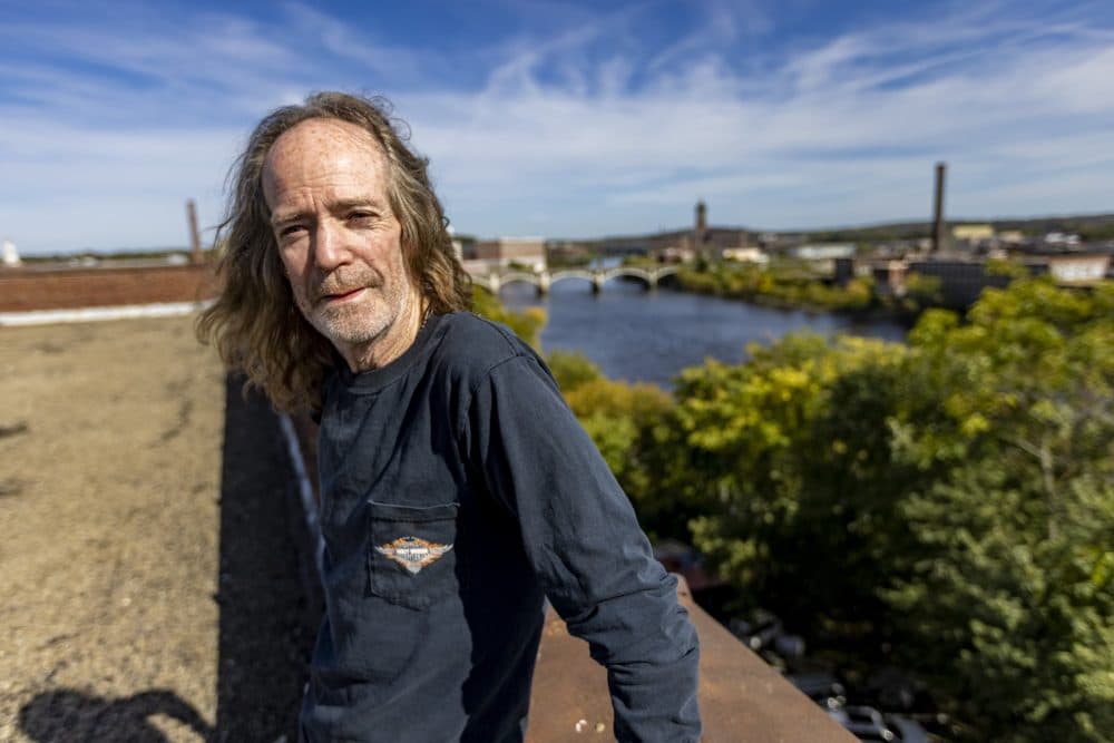 Andy Kelley on the rooftop of his furniture warehouse, where the Merrimack River runs behind it in downtown Lawrence. (Jesse Costa/WBUR)