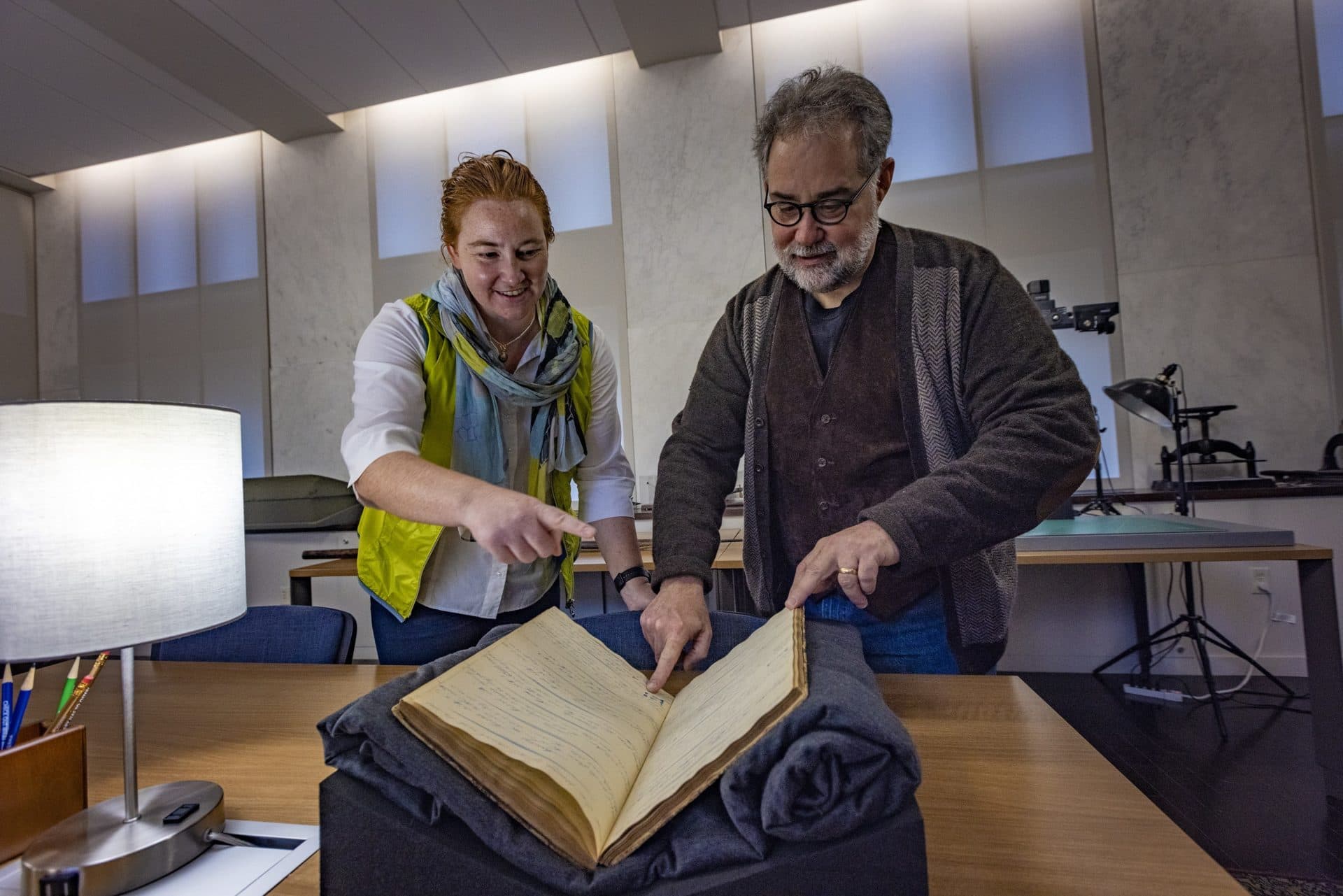 At the Providence Public Library, Caroline Ummenhofer, oceanographer at Woods Hole Oceanographic Institute, and Timothy Walker, history professor at UMass Darmouth, point out some of the weather features noted in the log book of the Ship Lion, during its voyage to the South Pacific between 1841-1844. (Jesse Costa/WBUR)