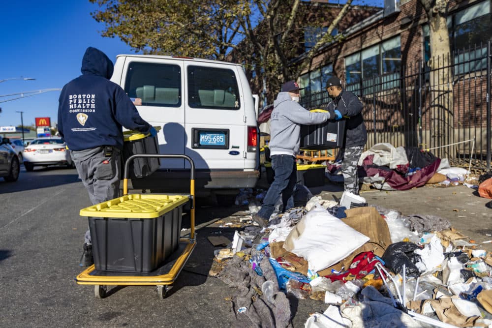 A Boston Public Health Commission worker loads bins full of belongings into a van on Southampton Street. They will be taken to a storage facility and held for up to 90 days. (Jesse Costa/WBUR)