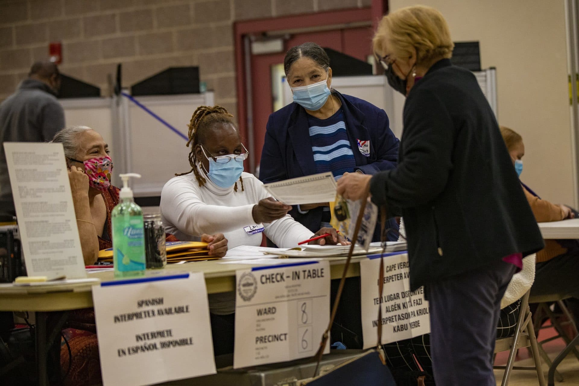 A voter receives her ballot at Ward 8 Precinct 6 polling station at the Ray and Joan Kroc Community Center in Dorchester in the early morning of Election Day. (Jesse Costa/WBUR)