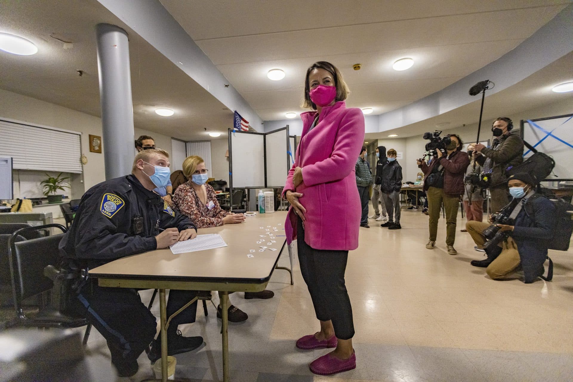 Candidate for mayor of Boston Annissa Essaibi George playfully looks at the press and hides her ballot underneath her coat to keep prying eyes from seeing it before approaching the ballot box at the Bellflower Apartments in Dorchester. (Jesse Costa/WBUR)