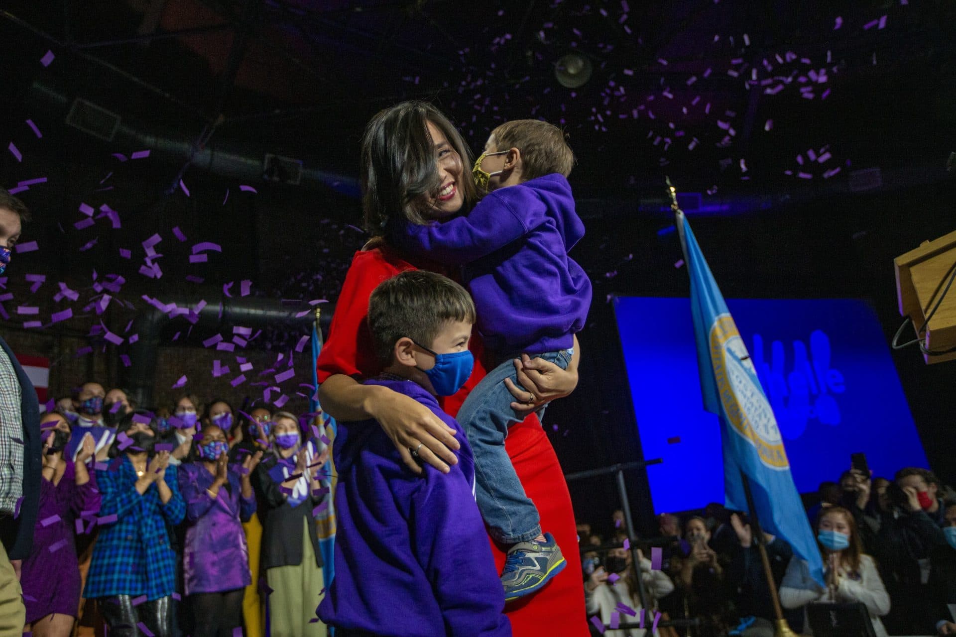 Newly elected mayor of Boston Michelle Wu embraces her sons Cass and Blaise on stage at the Cyclorama. (Jesse Costa/WBUR)