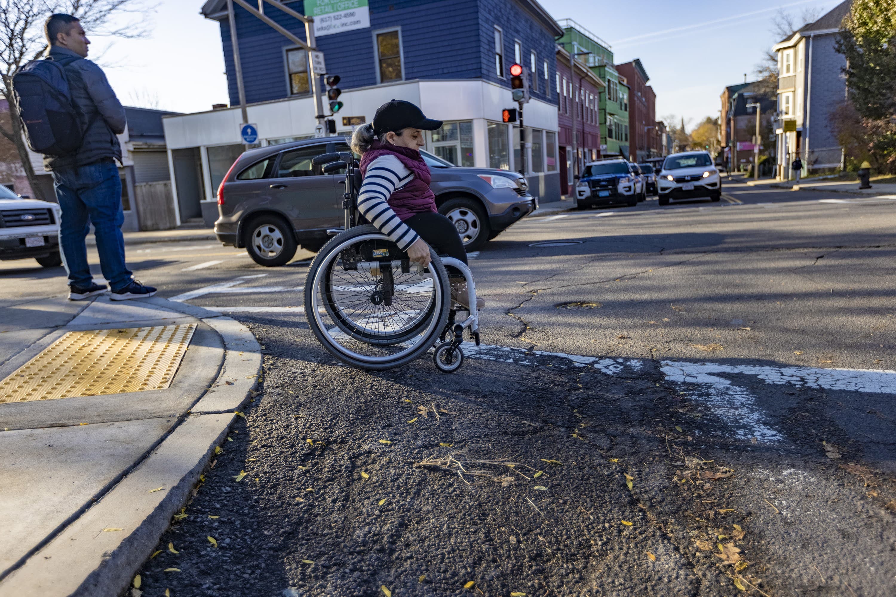 Colleen Flanagan navigates down a tall and somewhat steep curb ramp on at the corner of Washington Street and Glen Road in Jamaica Plain. (Jesse Costa/WBUR)