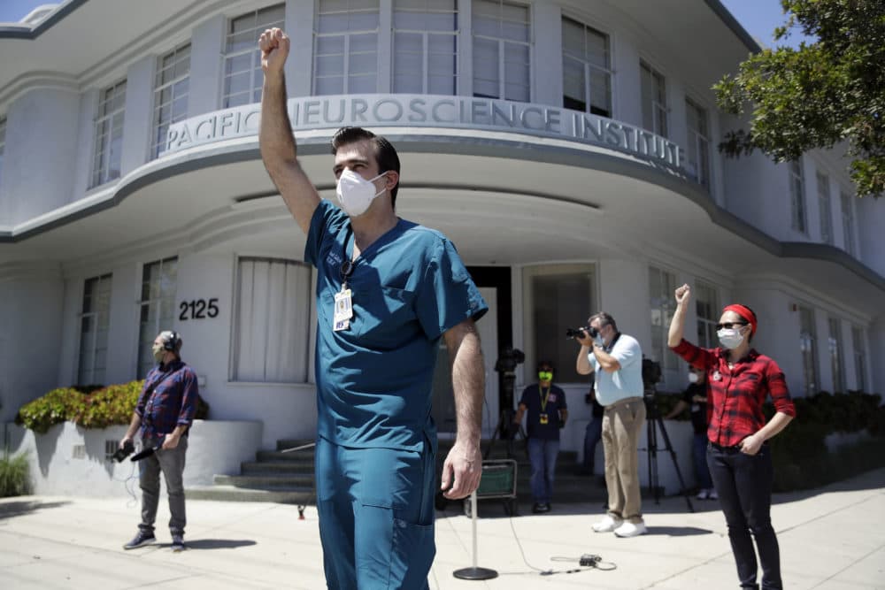 Michael Gulick, center, and Angela Gatdula, right, hold their arms up in protest outside of Providence Saint John's Health Center in Santa Monica, Calif. (Marcio Jose Sanchez/AP Photo)