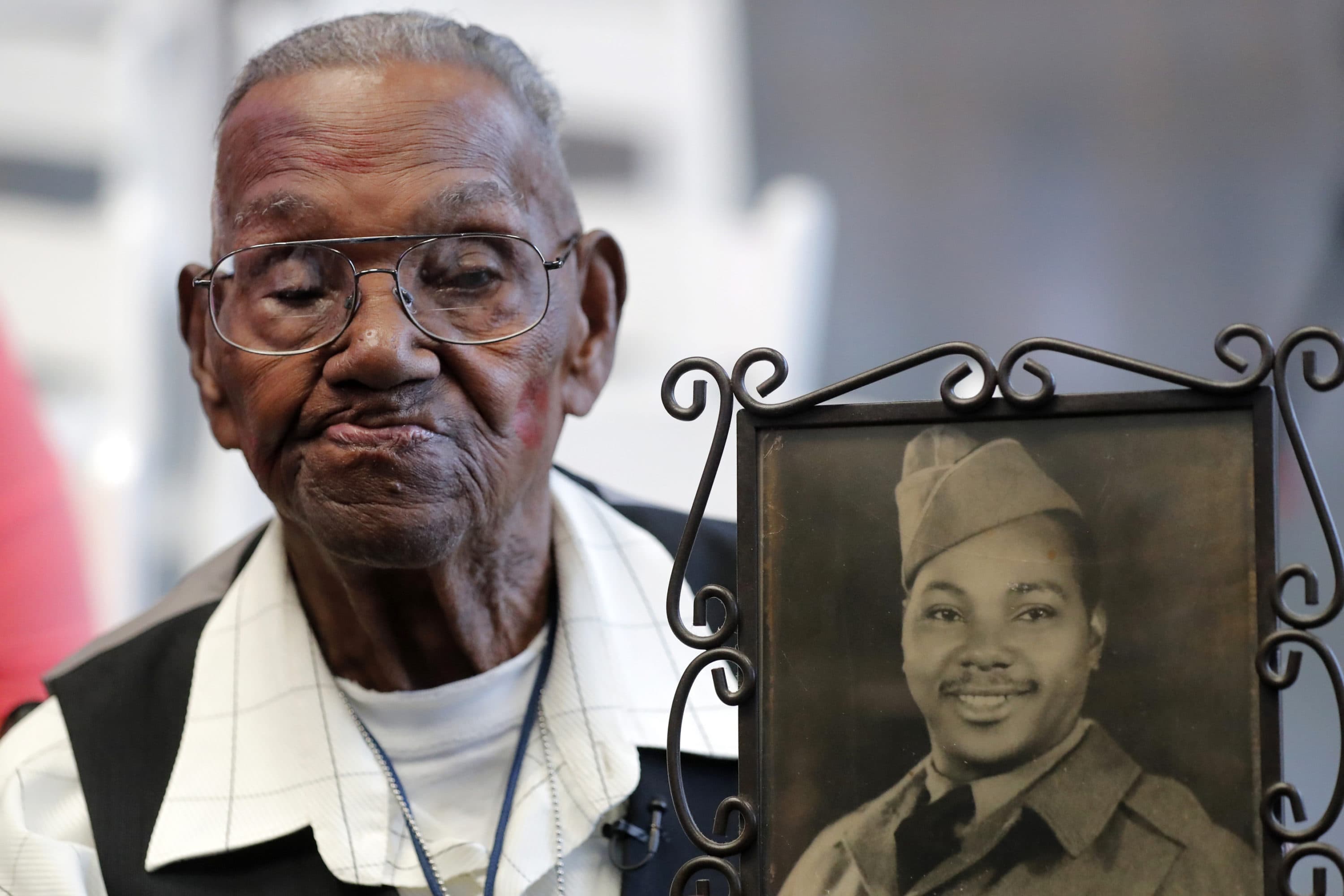 World War II veteran Lawrence Brooks holds a photo of him taken in 1943, as he celebrates his 110th birthday at the National World War II Museum in New Orleans, on Sept. 12, 2019. (AP Photo/Gerald Herbert, File)