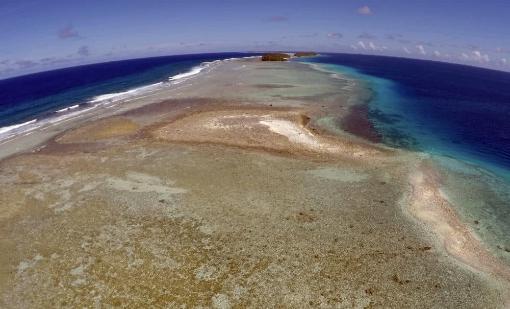 A small uninhabited island that has slipped beneath the water line only showing a small pile of rocks at low tide on Majuro Atoll in the Marshall Islands. Climate change poses an existential threat to places like the Marshall Islands, which protrude only 6 feet above sea level in most places. (Rob Griffith/AP)