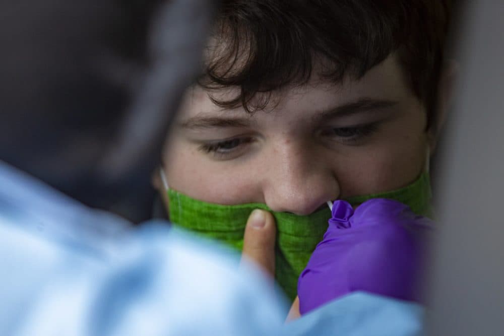 Jessica Capobianco performs a COVID test on 14-year-old Brady Martel at the Bromfield School in Harvard, Mass. (Jesse Costa/WBUR)