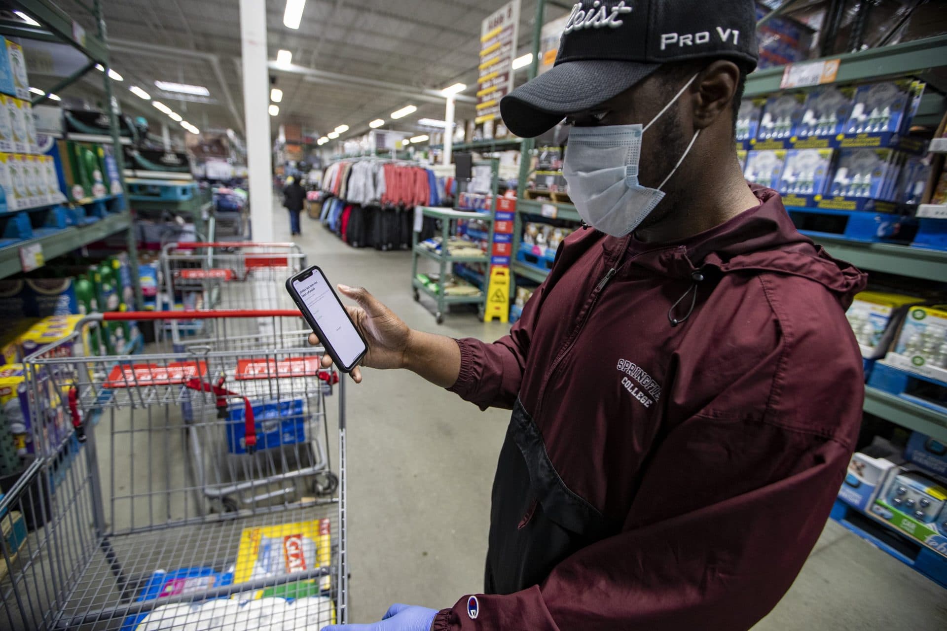 Instacart shopper Shamar Martin looks at his app while shopping on April 18, 2020. (Jesse Costa/WBUR)