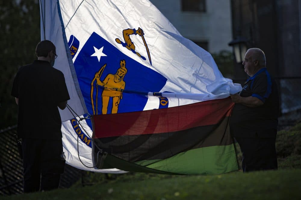Workers prepare to raise the red, black and green Pan-African flag in front of the State House to commemorate the first Juneteenth holiday recognized by the state. (Jesse Costa/WBUR)