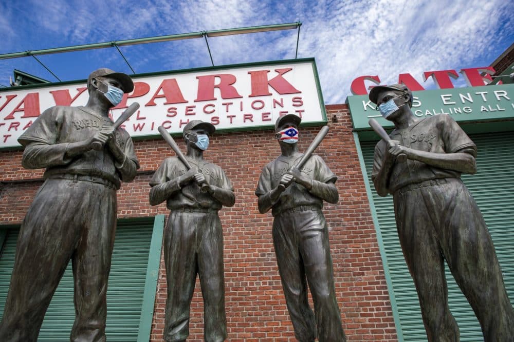 The statues of Ted Williams, Bobby Doerr,  Johnny Pesky and Dom DiMaggio wear masks outside of Fenway Park. (Jesse Costa/WBUR)