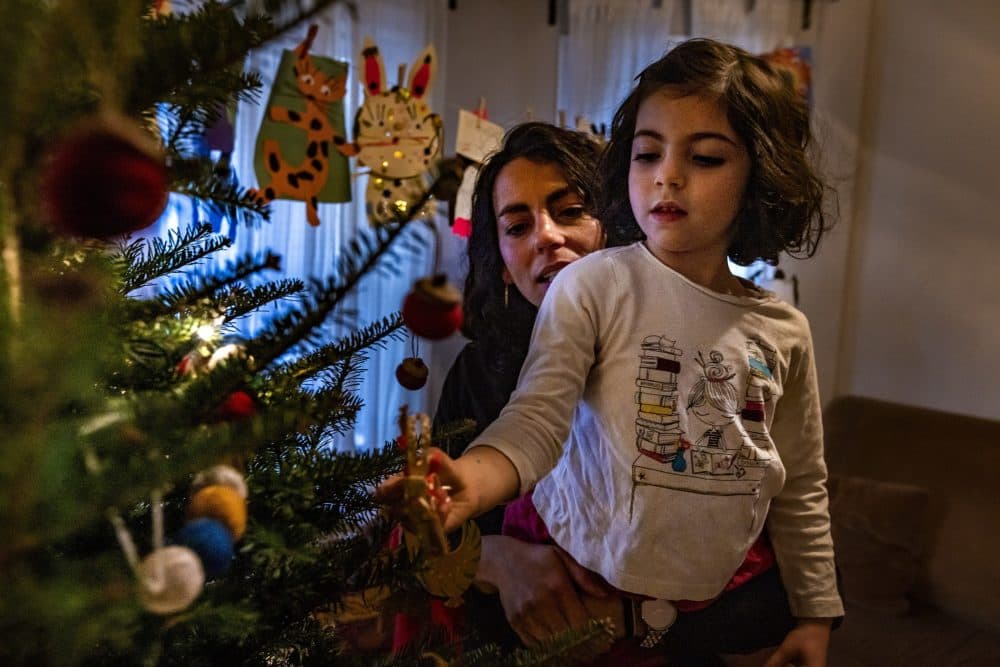 Mei Elensary and her daughter, Mimi, look at ornaments on their Christmas tree on a day Mimi will not attend school after an announcement was made one of her classmates tested positive with the COVID-19 virus. (Jesse Costa/WBUR)