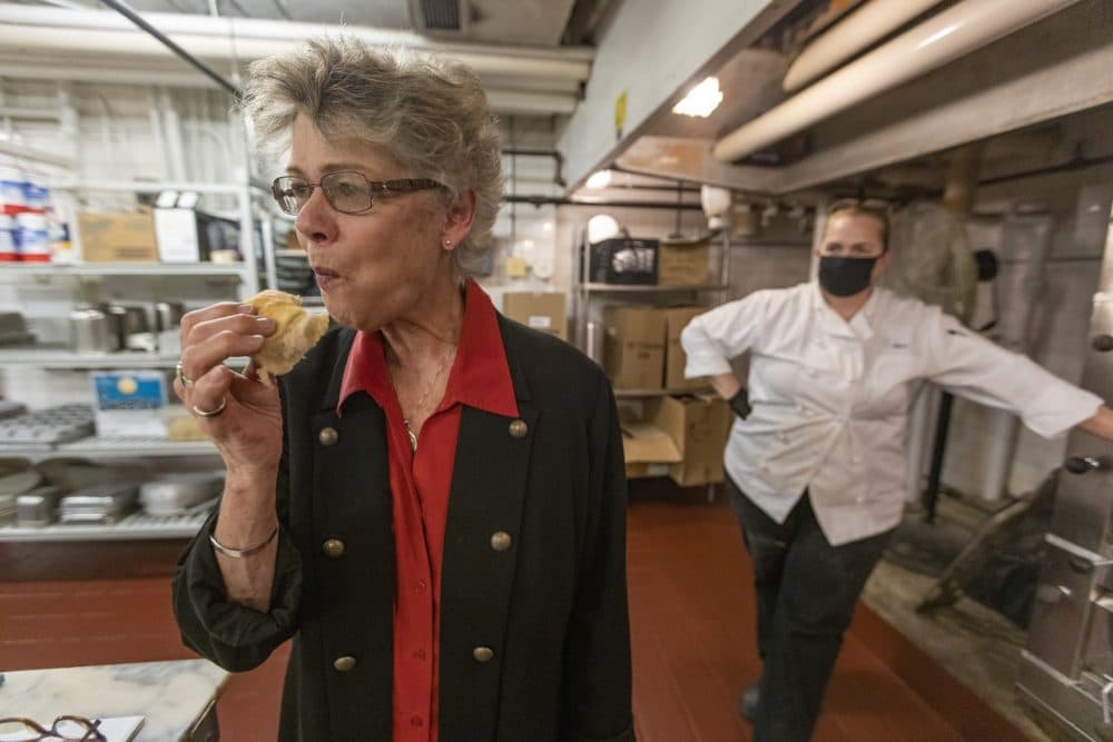 The hotel's historian, Susan Wilton, samples one of the Parker House rolls just out of the oven as baker Sheri Weisenberger watches for her assessment. (Jesse Costa/WBUR)