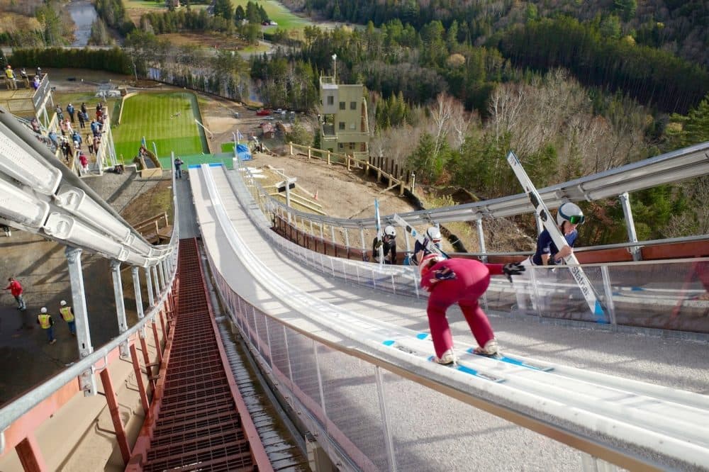 A ski jumper goes down the inrun at the recently upgrade Olympic ski jumps in Lake Placid. (Emily Russell/North Country Public Radio)