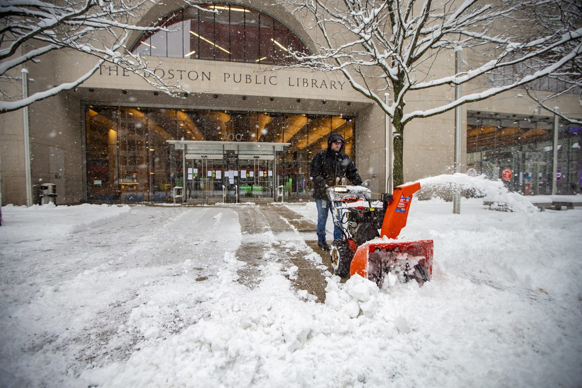 A worker uses a snow blow to clear snow in front of the Boston Public Library on Friday morning. (Jesse Costa/WBUR)