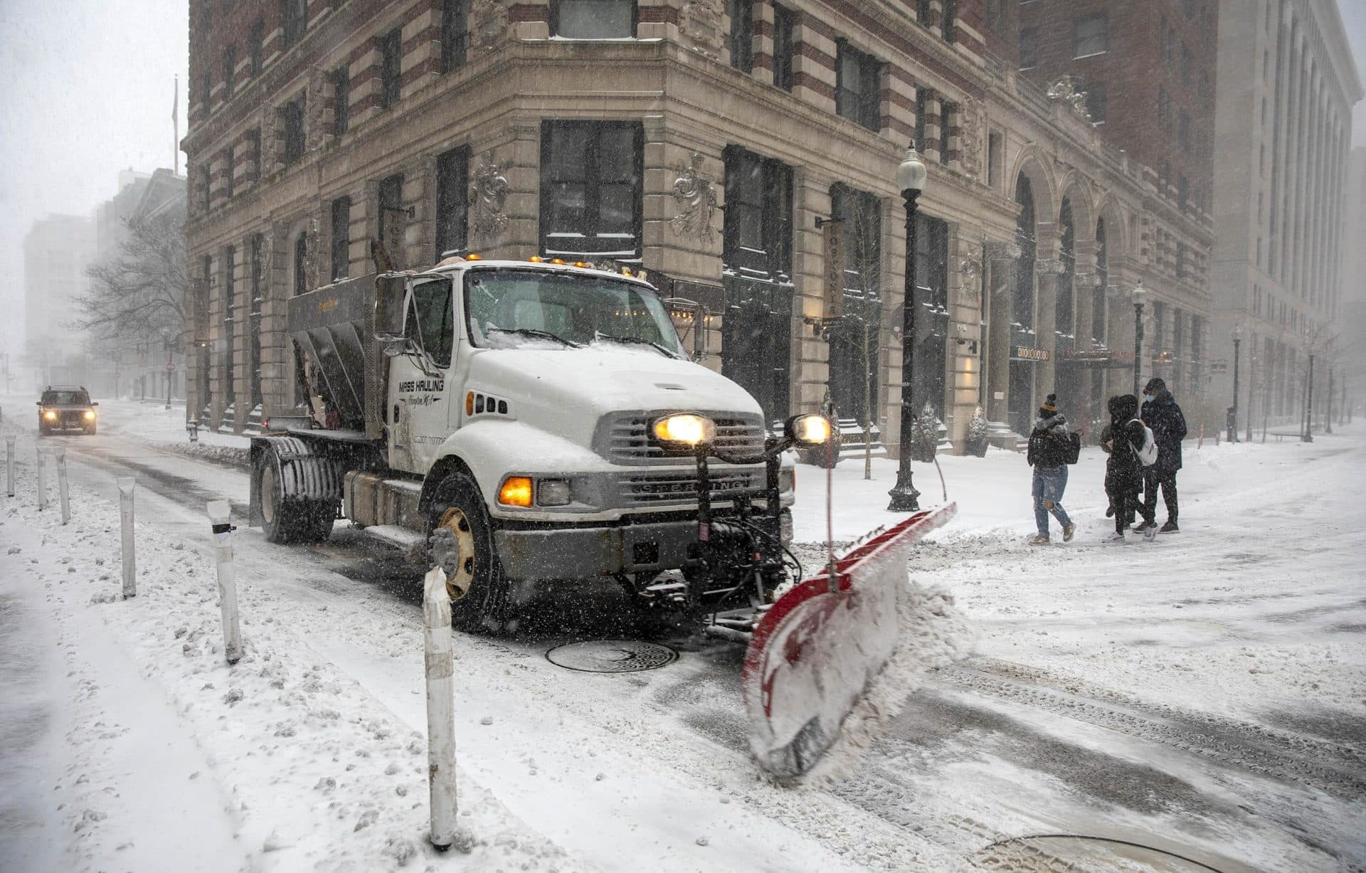 A snow plow moves up State Street, as steady snow falls on Boston. (Robin Lubbock/WBUR)