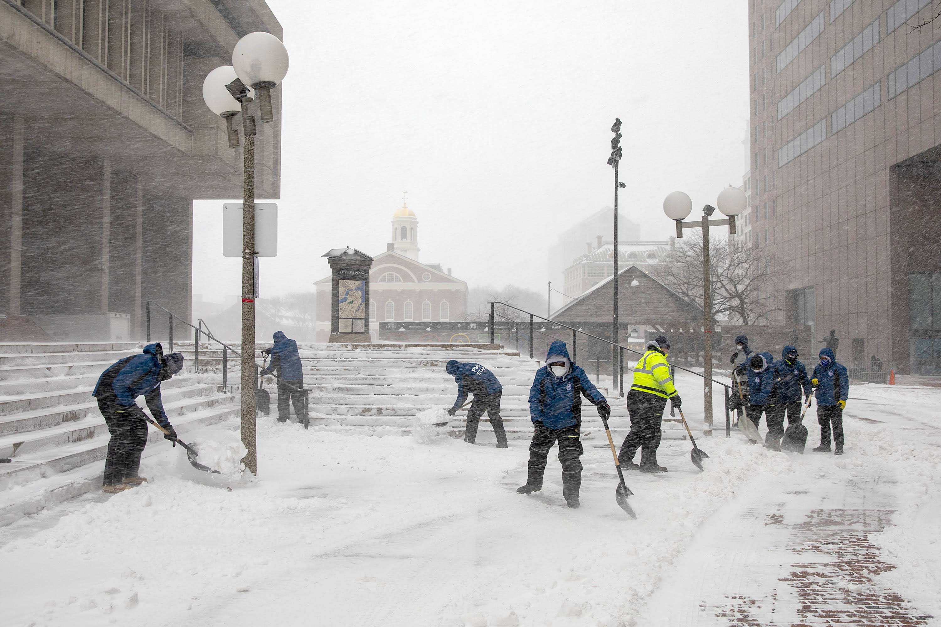A the snowstorm sets in, a crew of workers clears the steps of Boston City Hall. (Robin Lubbock/WBUR)