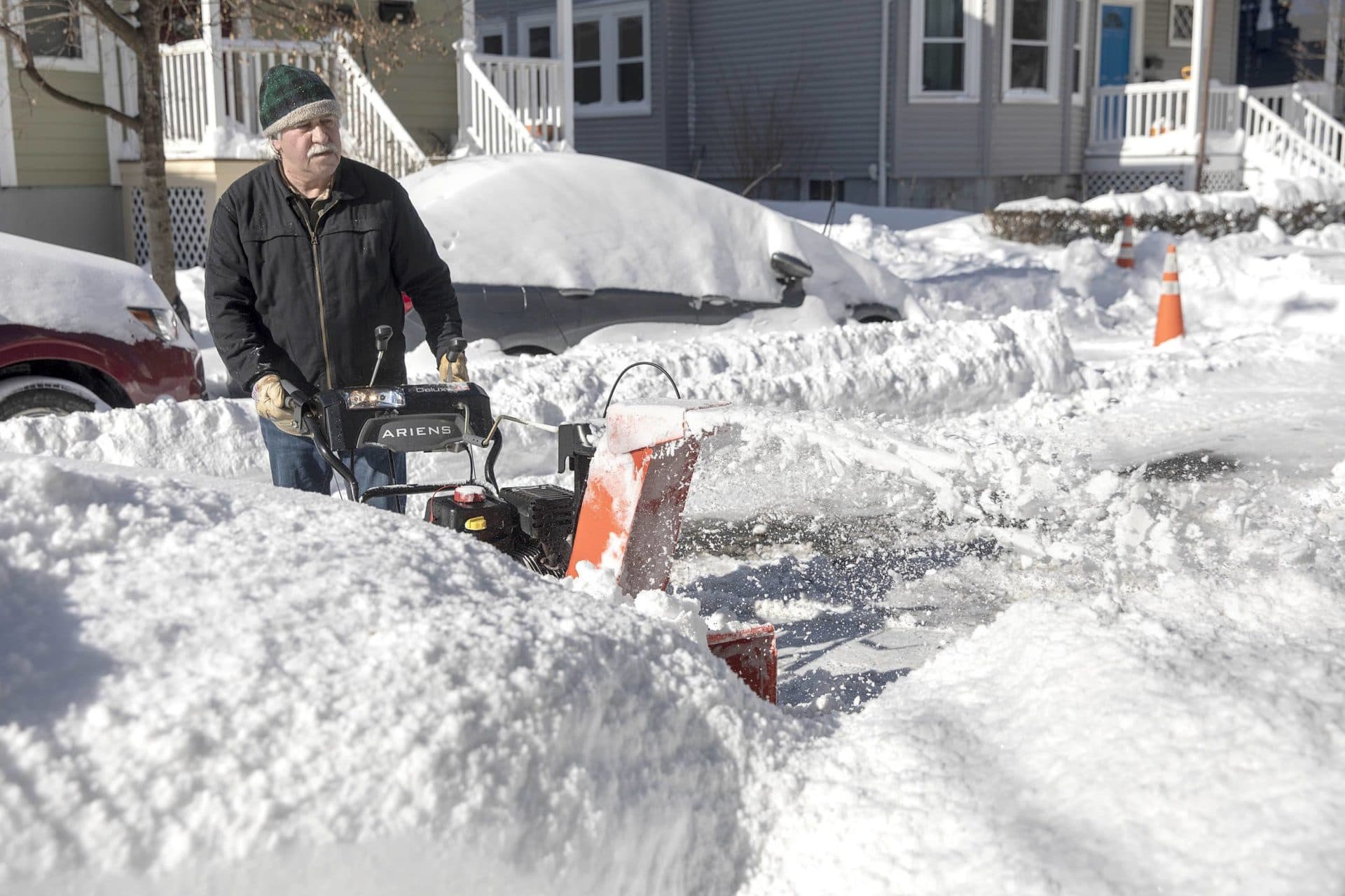 Don Drisdell uses his snowblower to start digging out his neighbor's car in Cambridge. (Robin Lubbock/WBUR)
