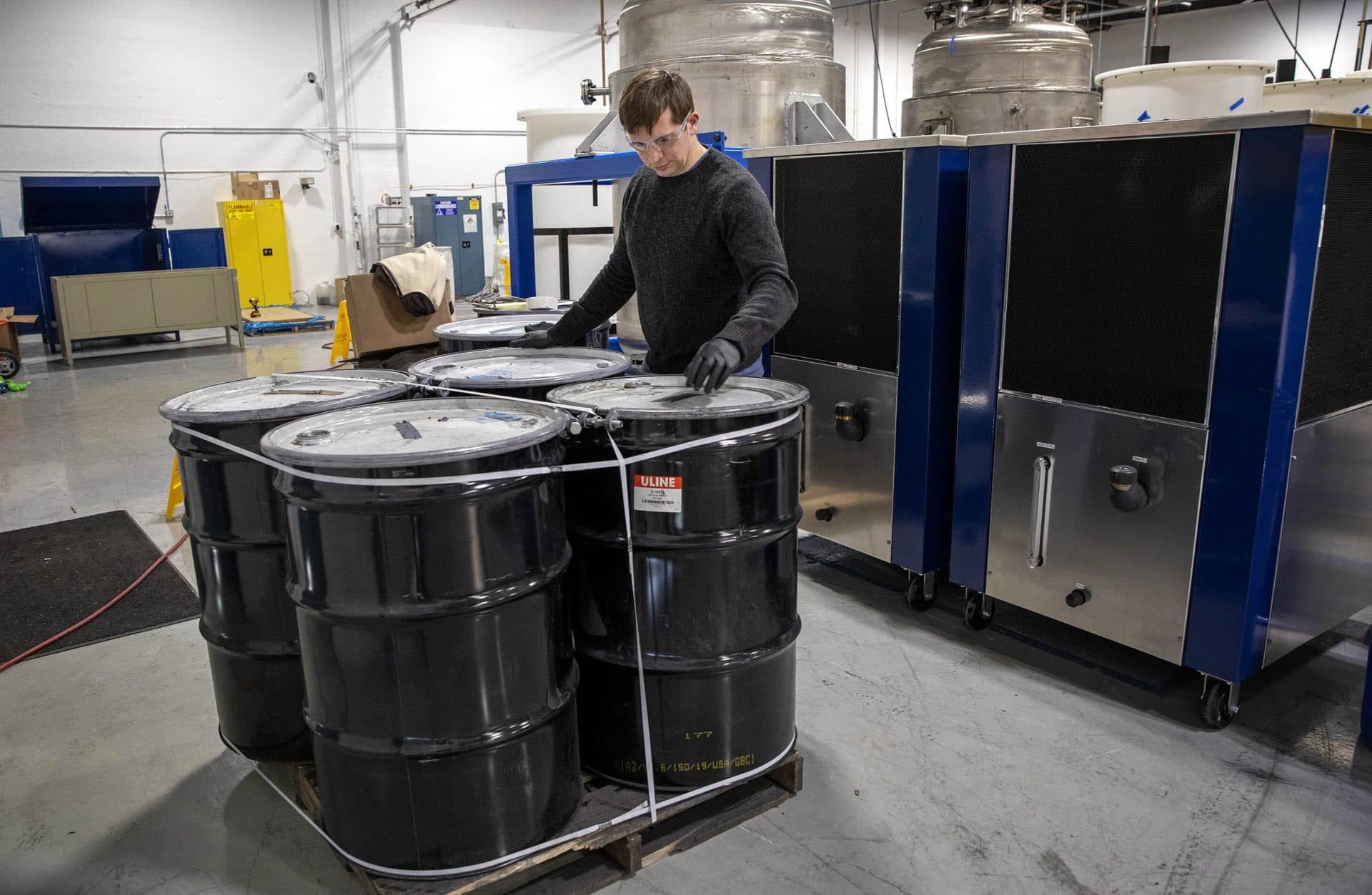 Eric Gratz, co-founder of Ascend Elements, examines barrels of &quot;black mass&quot; powder, made from shredded lithium batteries. (Robin Lubbock/WBUR)