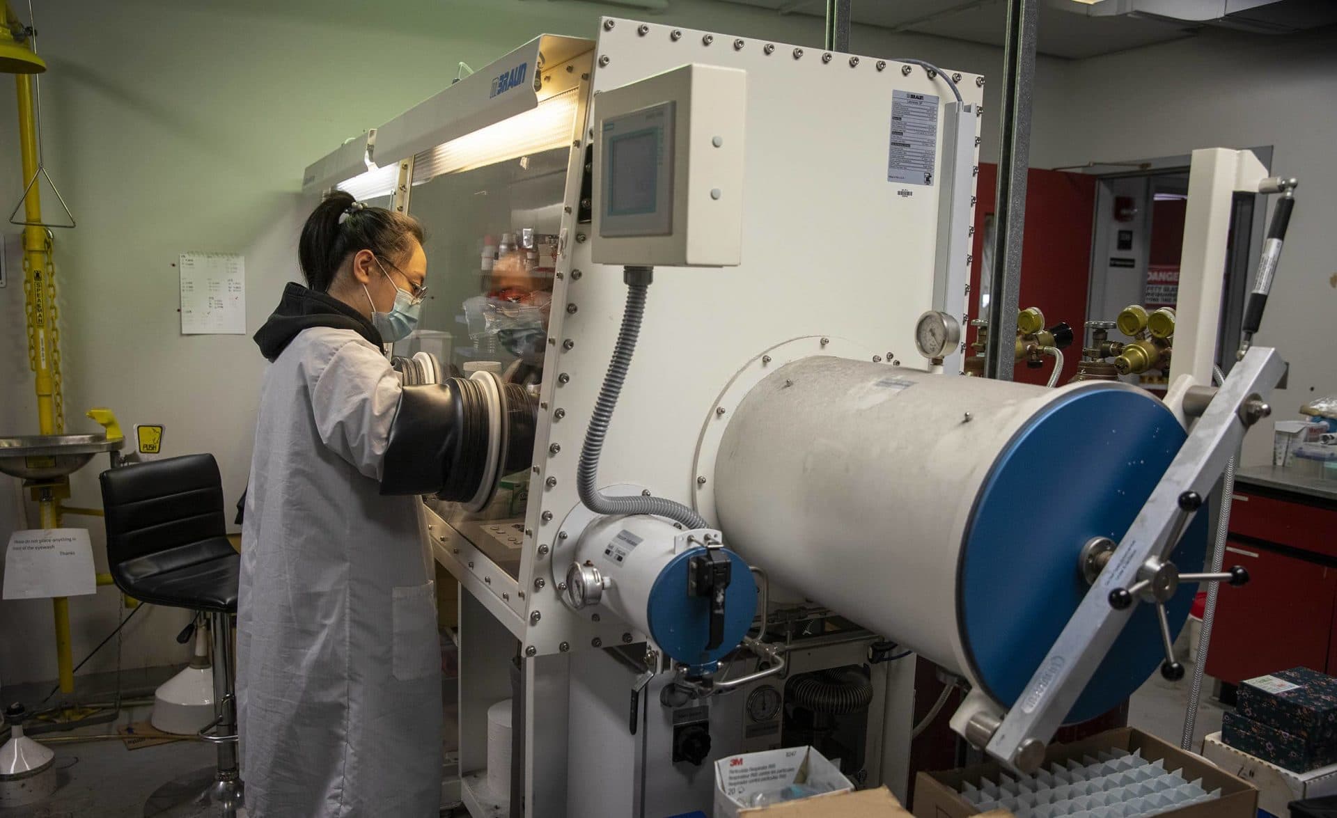 Jiahui Hou assembles coin batteries in a low oxygen work bench at Worcester Polytechnic Institute. (Robin Lubbock/WBUR)