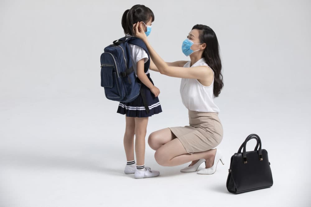A mother puts a mask on her daughter. (Getty Images)