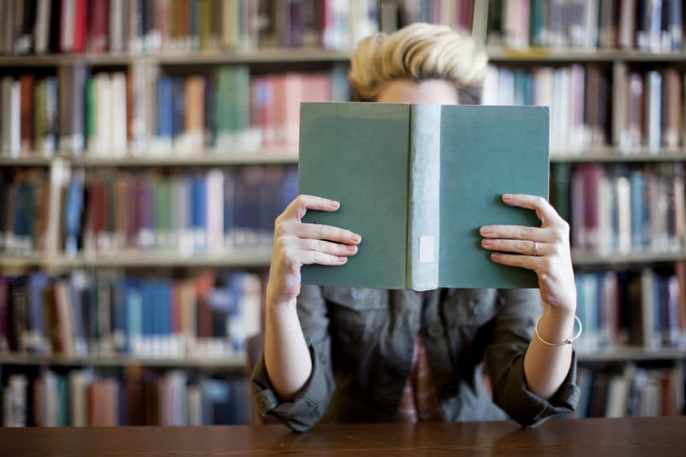 Woman reading book in library. (Getty images)