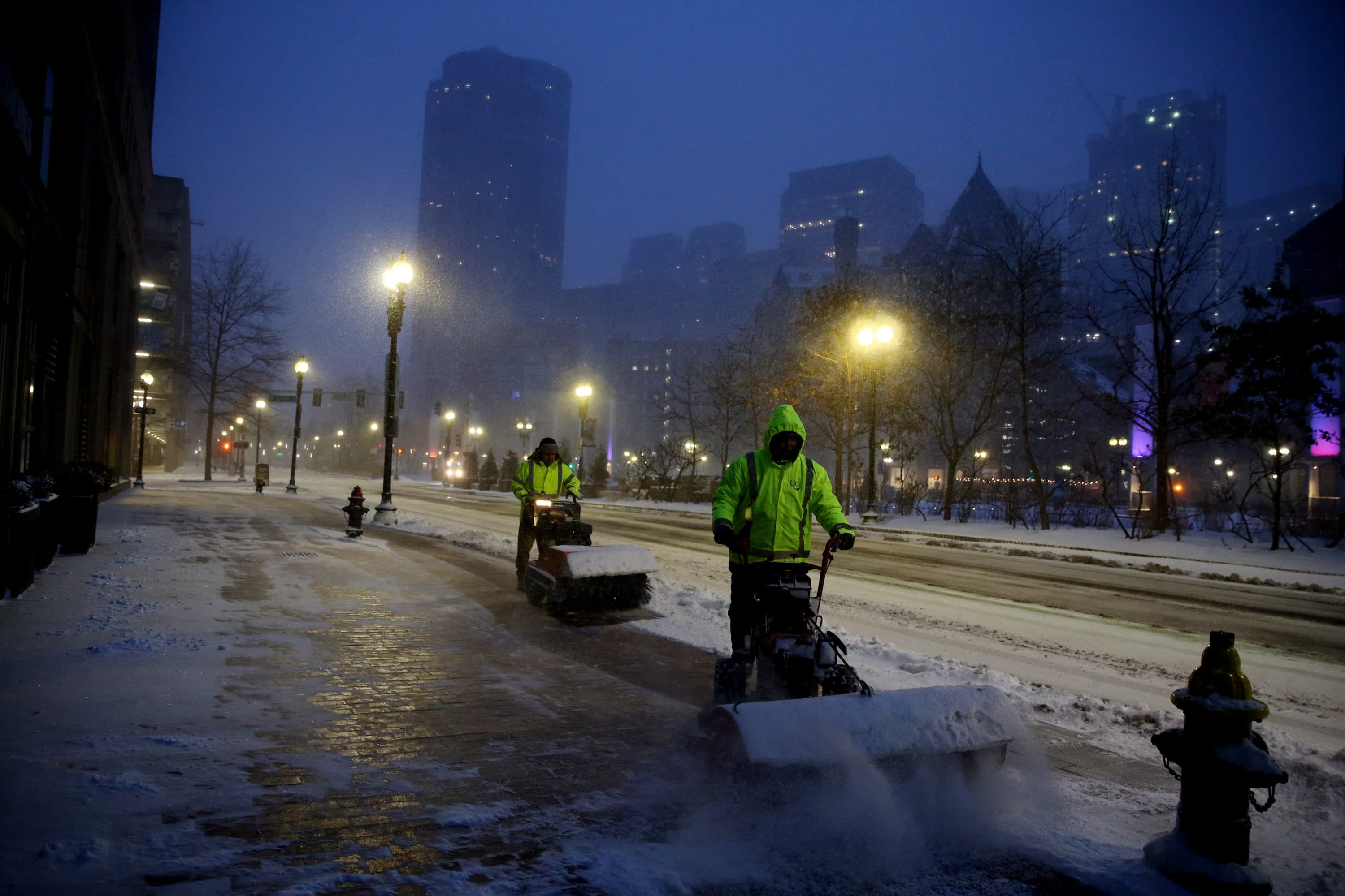 Workers clear sidewalks during the snowstorm in downtown Boston Saturday. (Craig F. Walker/The Boston Globe via Getty Images)