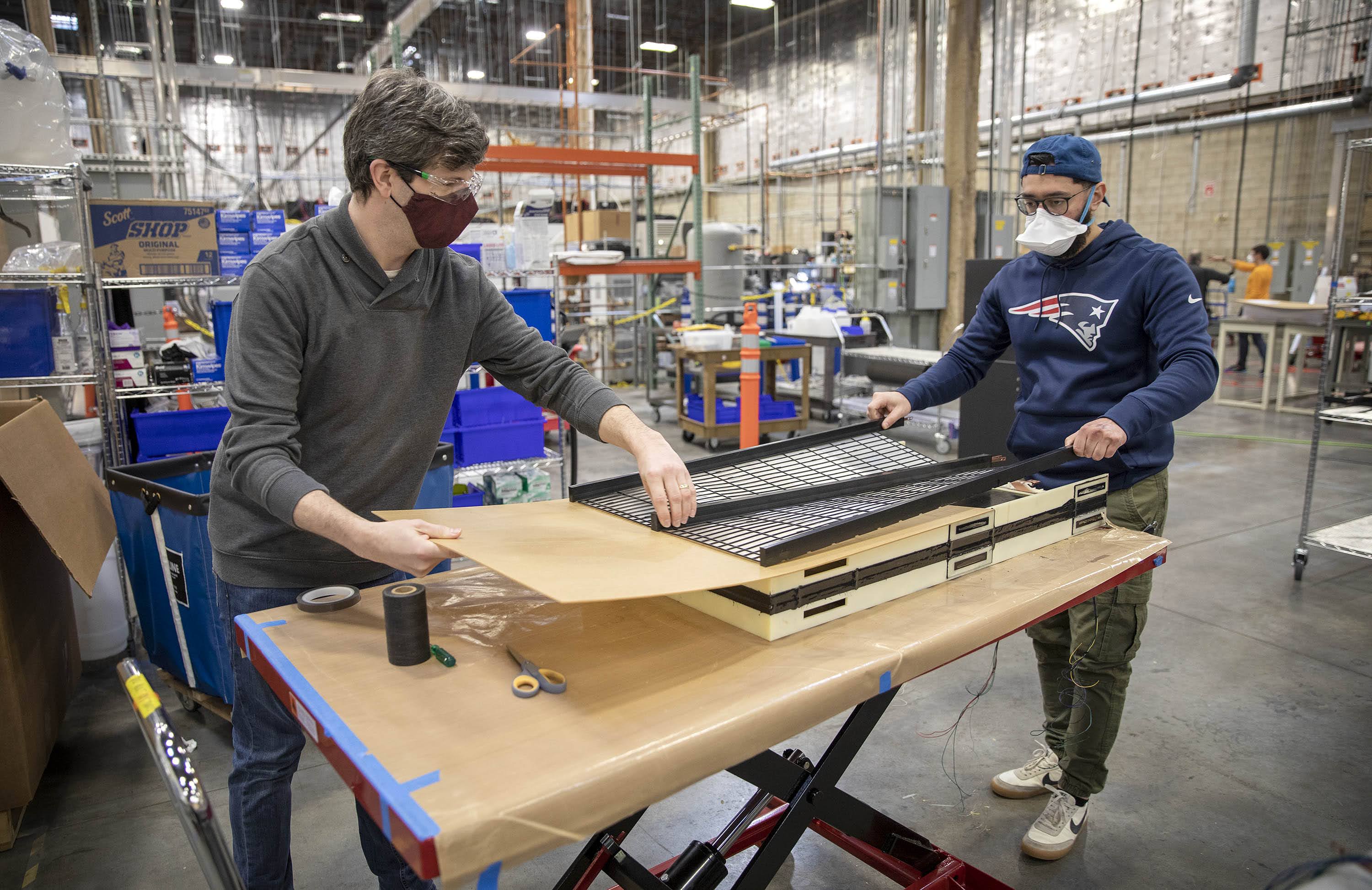 Mechanical engineer Ken Barnett and technician Juan Martinez at work constructing an iron-air battery at Form Energy's facility in Somerville. (Robin Lubbock/WBUR)