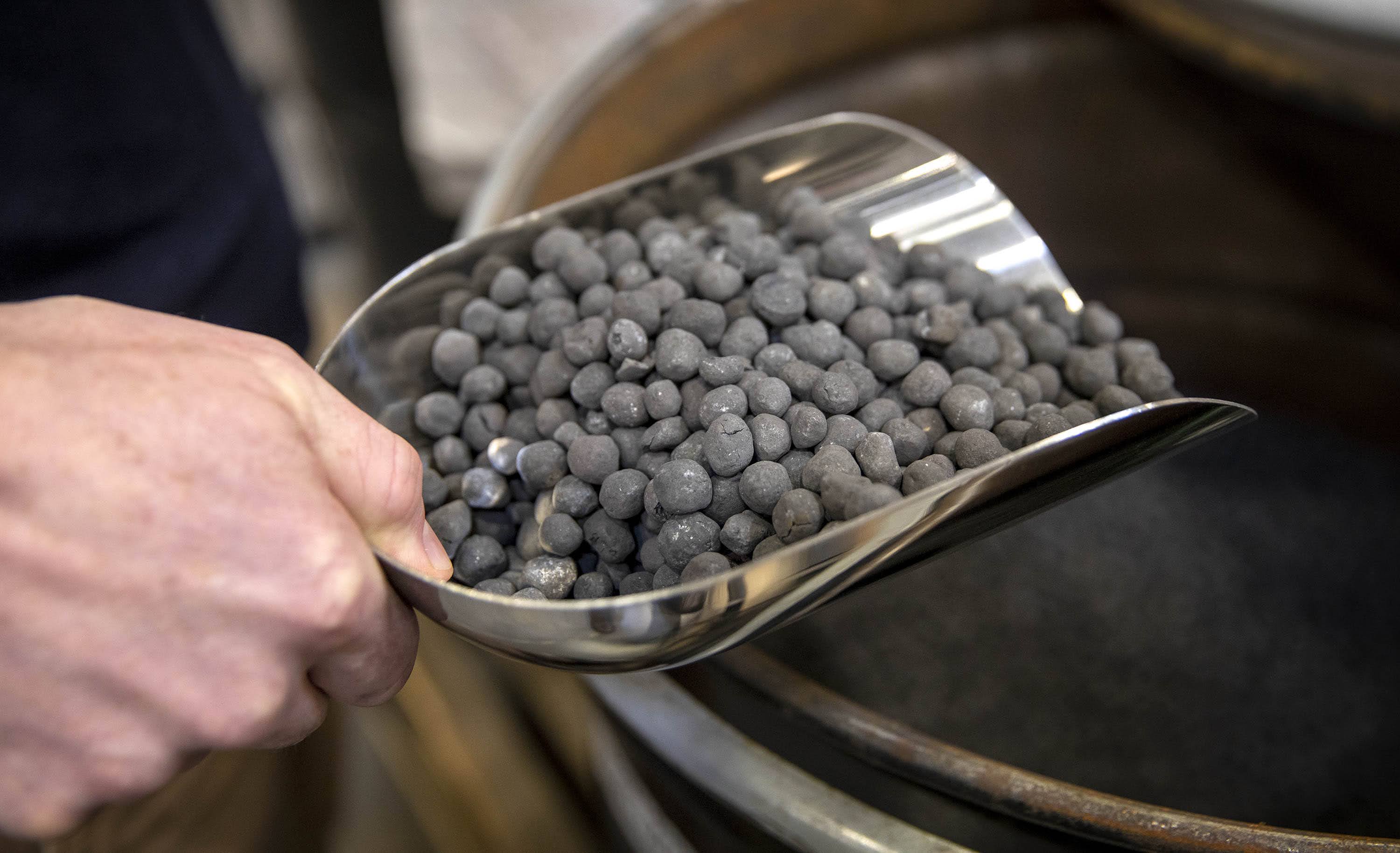 A scoop of iron pellets, one of the cheap and abundant raw materials of iron-air batteries. (Robin Lubbock/WBUR)