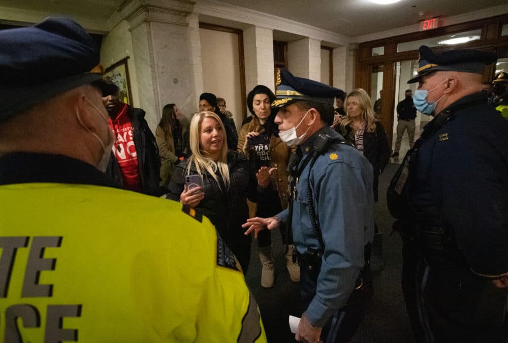 A protester talks to a State Police major after he advised the small group that they were unlawfully assembled during a protest inside the State House. (Sam Doran/SHNS)