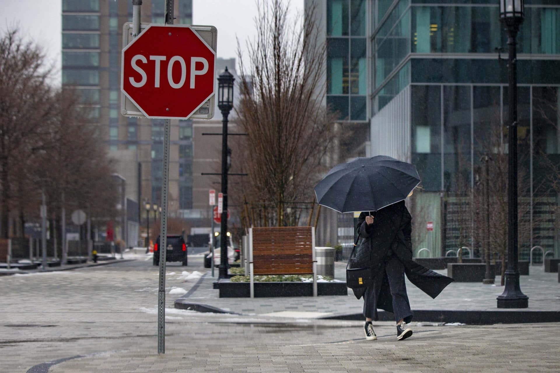 A woman with an umbrella walks down Marina Park Drive in the Seaport during the storm. (Jesse Costa/WBUR)