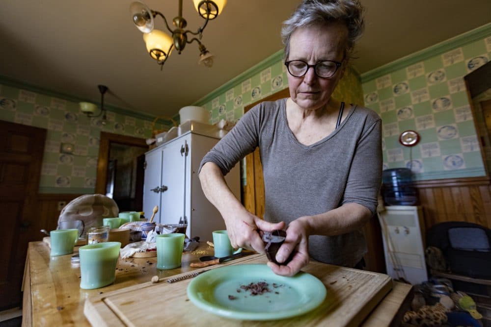 Food historian Paula Marcoux shaves chocolate onto a plate in preparation to make hot chocolate. (Jesse Costa/WBUR)