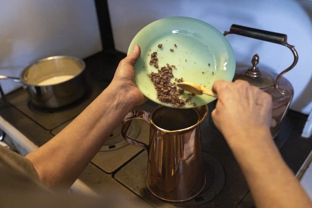 Food historian Paula Marcoux puts shaved chocolate a copper pitcher of hot water to make hot chocolate. (Jesse Costa/WBUR)