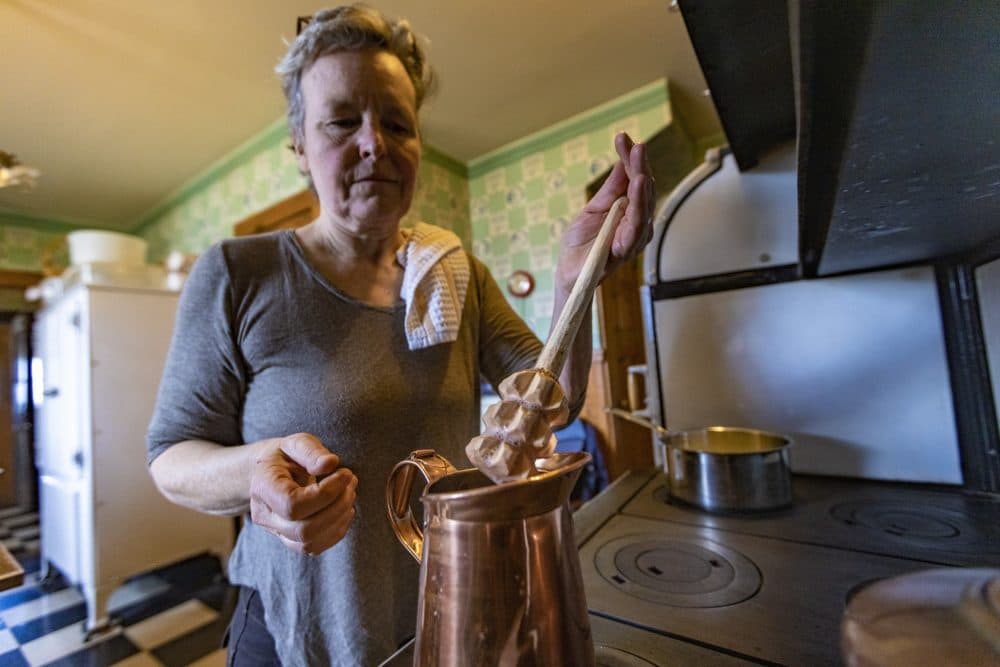 Food historian Paula Marcoux prepares to place a wooden mixing tool into the copper pitcher with the chocolate mixture. The tool is a handmade replica based on paintings and drawings from the Colonial period. (Jesse Costa/WBUR)