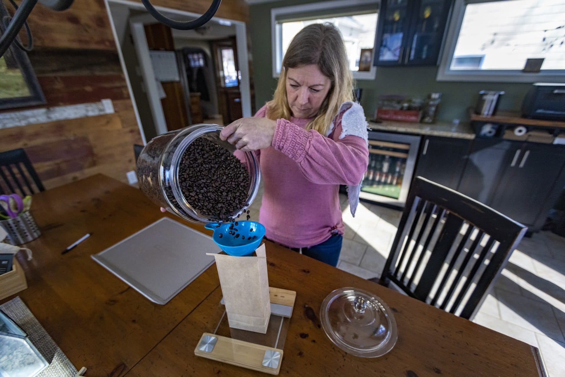 Amy Smith pours freshly roasted coffee into a bag at her home business My Coffeesmiths in Pembroke. (Jesse Costa/WBUR)