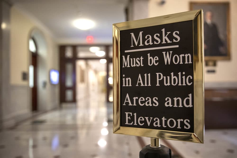 A sign in a hallway at the Massachusetts State House reminds visitors that masks must be worn in all public areas. (Robin Lubbock/WBUR)