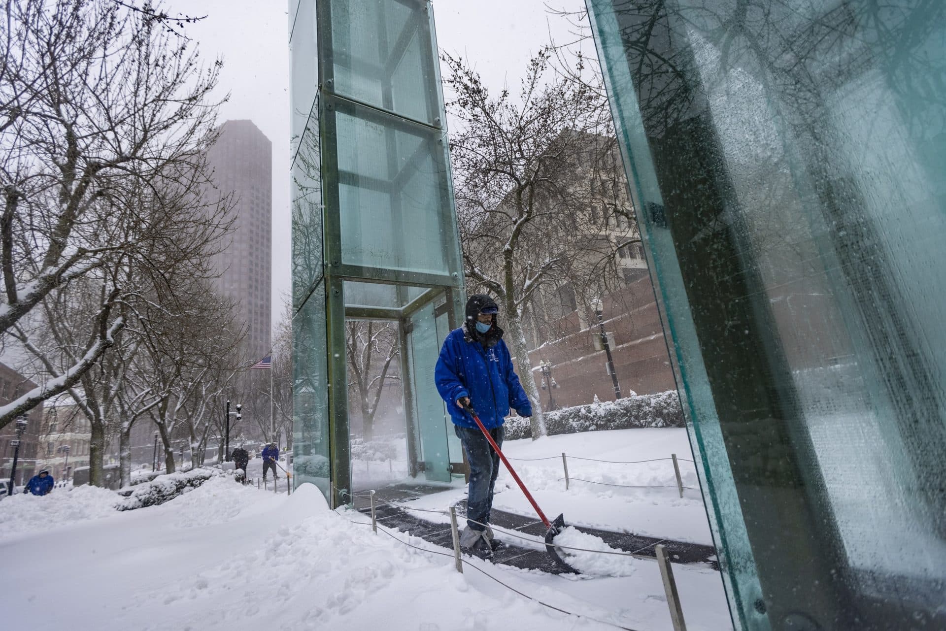 Workers clear snow from the New England Holocaust Memorial on Congress Street. (Jesse Costa/WBUR)