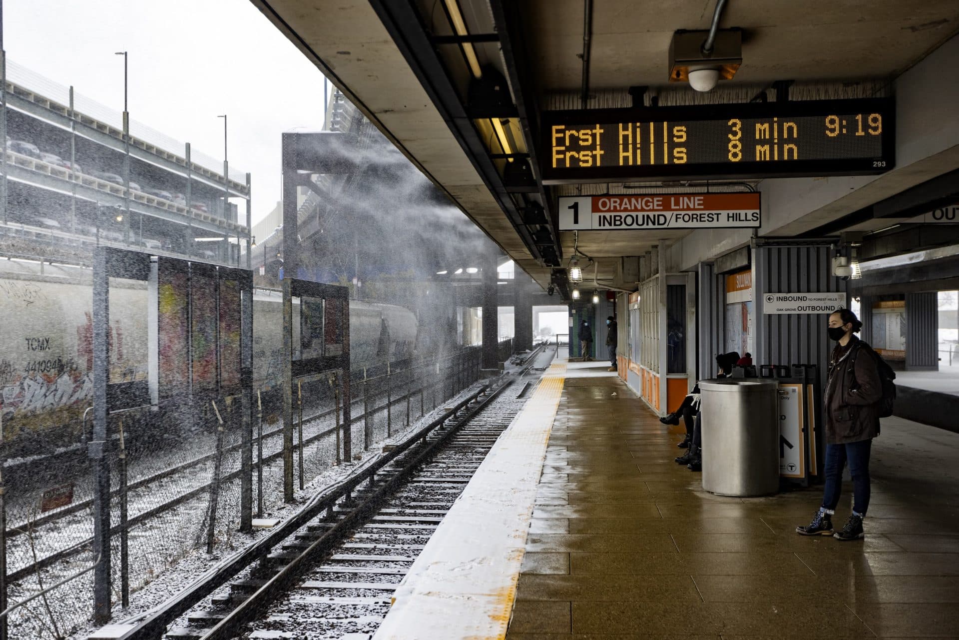 Wind-swept snow falls as riders wait for an MBTA Orange Line train in Sullivan Square Station. (Jesse Costa/WBUR)