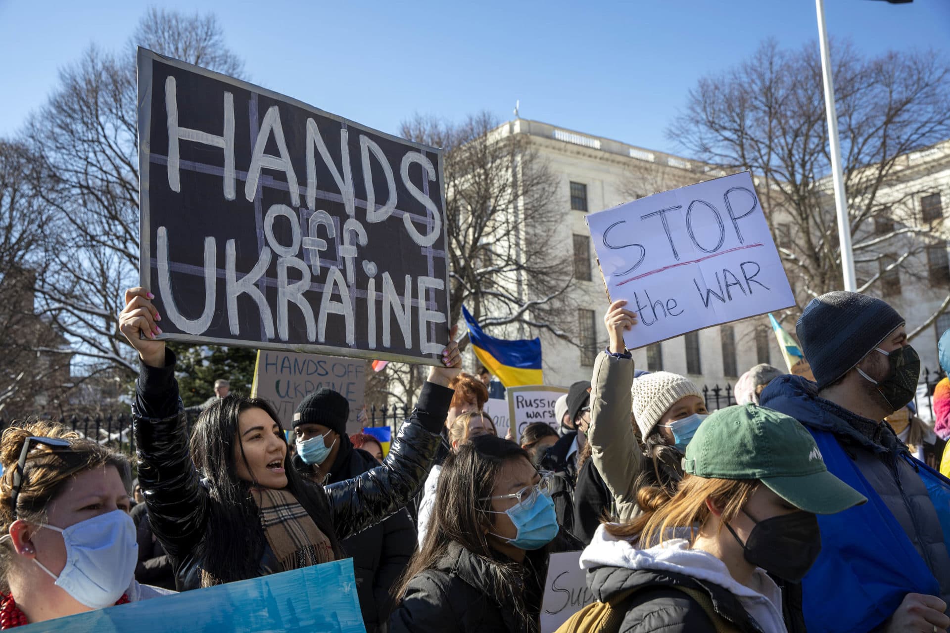 In front of the Massachusetts State House a demonstrator holds up a sign saying &quot;Hands off Ukraine.&quot; (Robin Lubbock/WBUR)
