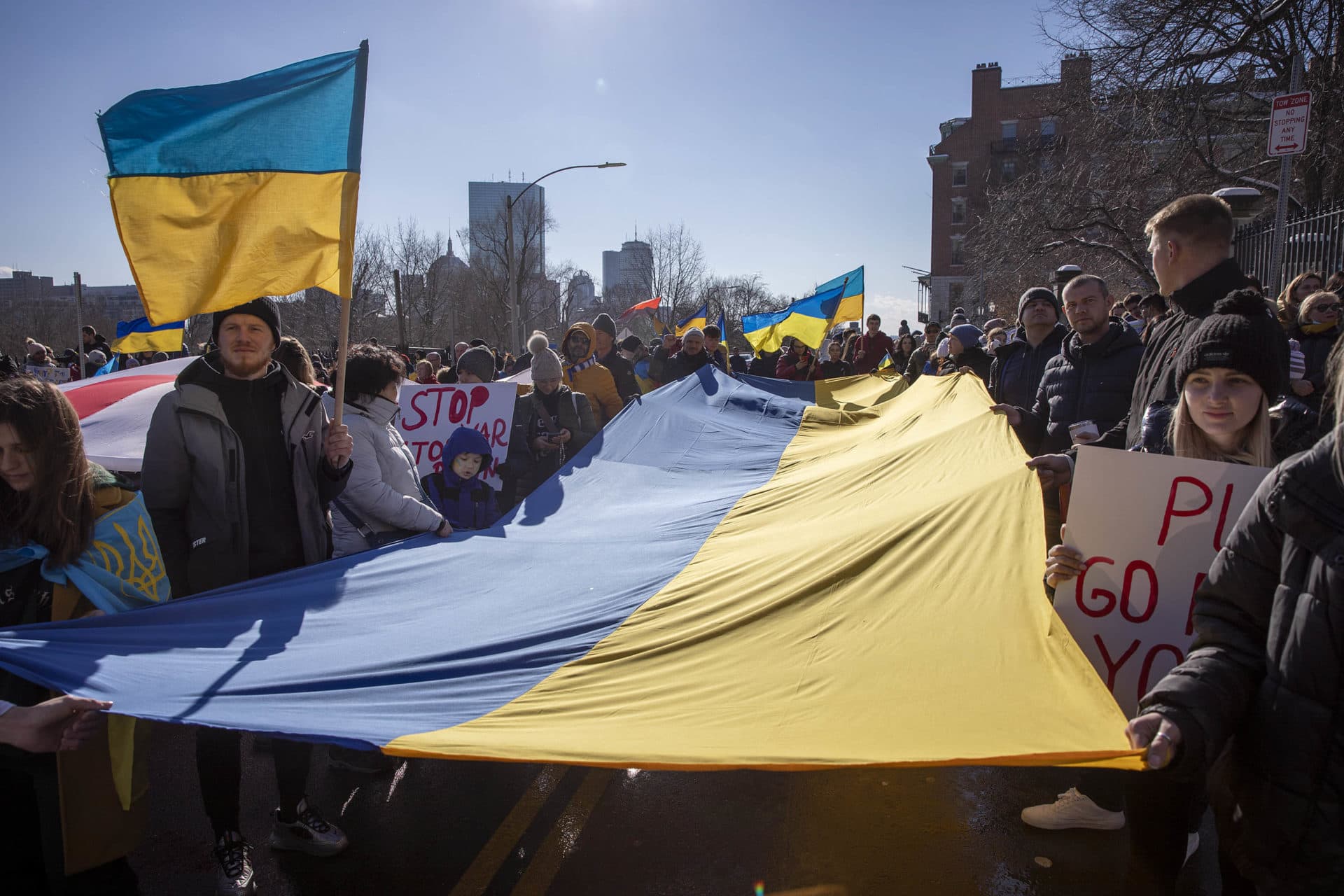 Demonstrators against the war in Ukraine carry a Ukrainian flag along Beacon Street by the Massachusetts State House. (Robin Lubbock/WBUR)