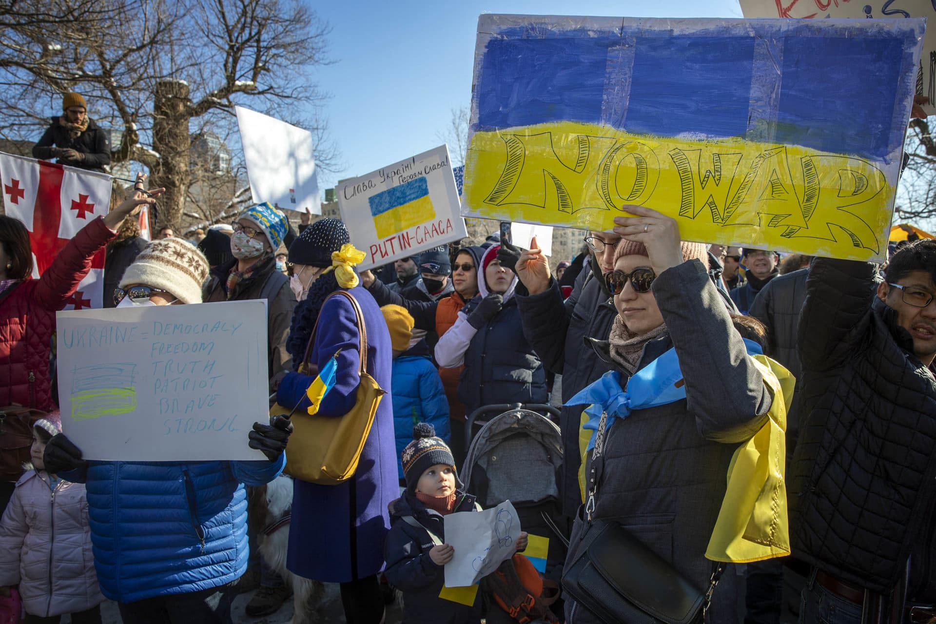 Outside the Mass. State House, Anna Khomenko holds up a sign saying "No War" during the demonstration against the war in Ukraine. (Robin Lubbock/WBUR)