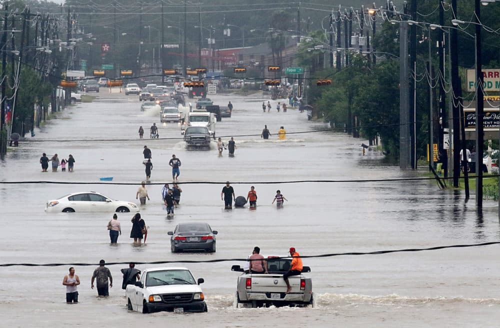 People walk through the flooded waters of Telephone Rd. in Houston on Aug. 27, 2017 as the U.S. fourth city battles with tropical storm Harvey and resulting floods. (Photo by Thomas Shea/AFP via Getty Images)