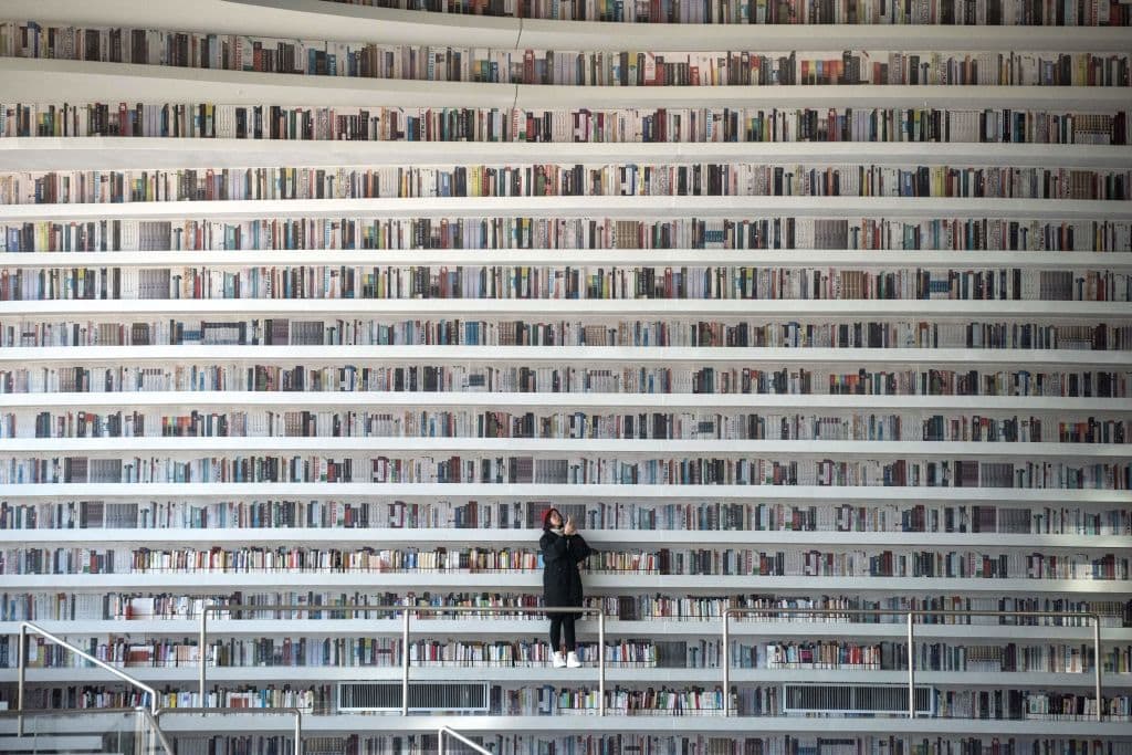 This picture taken on November 14, 2017 shows a woman taking pictures at the Tianjin Binhai Library, a futuristic Chinese library has wowed book lovers around the world with its white, undulating shelves rising from floor to ceiling. (Fred Dufour/AFP via Getty Images)