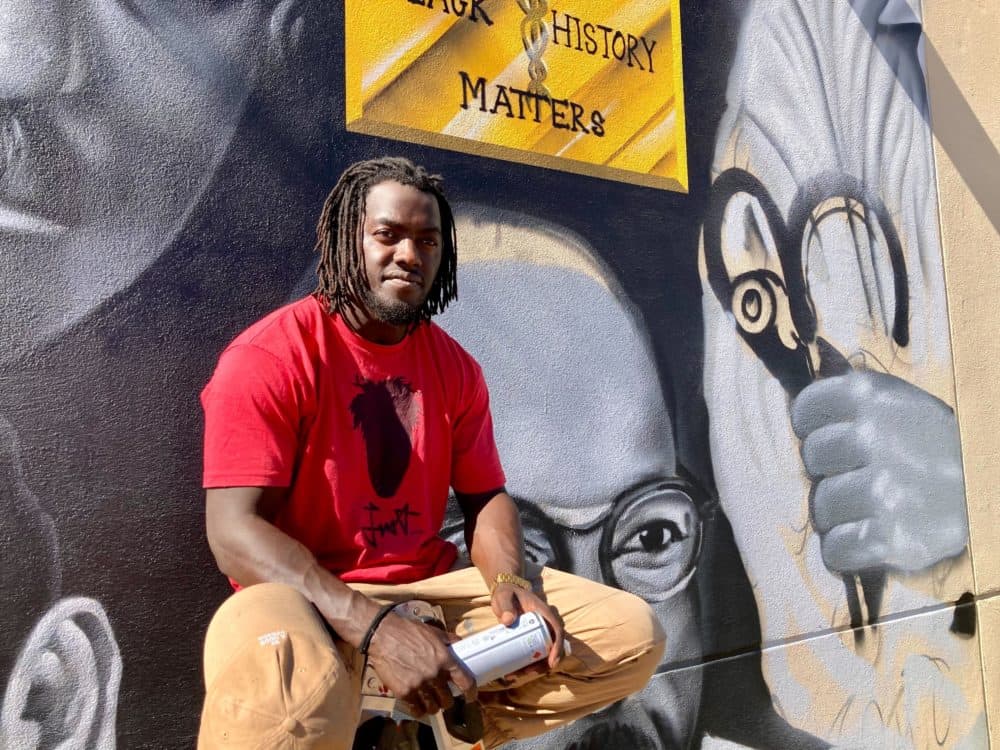 In downtown Phoenix, artist Giovannie Dixon is putting the finishing touches on a mural that depicts three pioneering Black doctors. It's part of the Shining Light Foundation's Black History mural project. (Peter O'Dowd/Here & Now)