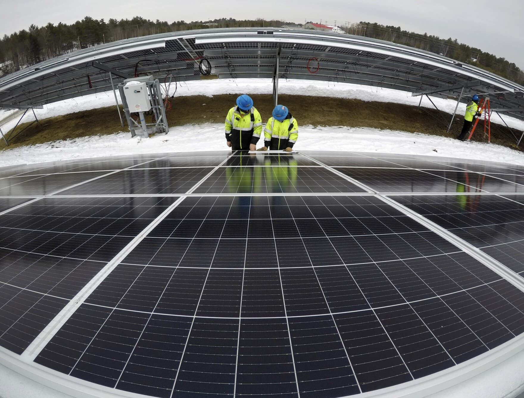 Electricians Bryan Driscoll and Zach Newton review a wiring schematic while installing solar panels at the 38-acre BNRG/Dirigo solar farm, Jan. 14, 2021, in Oxford, Maine. (Robert F. Bukaty/AP)