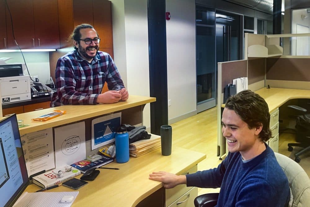 Jake DiMare (left) chats with a coworker at the Voicify office in Boston. (Yasmin Amer/WBUR)