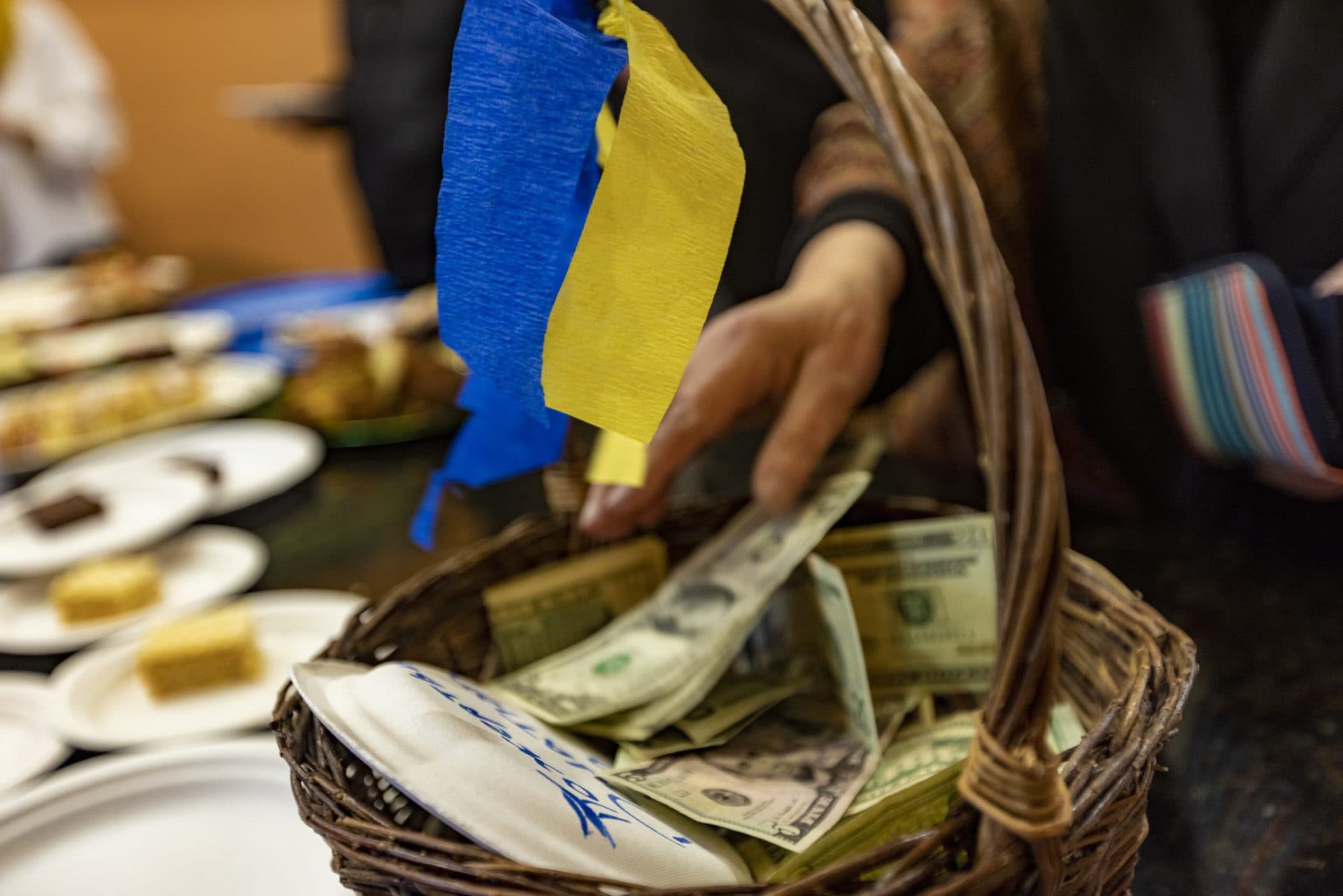 A basket with the colors of the Ukrainian flag filled with donations for Ukraine at Christ the King Ukrainian Catholic Church in Jamaica Plain. (Jesse Costa/WBUR)