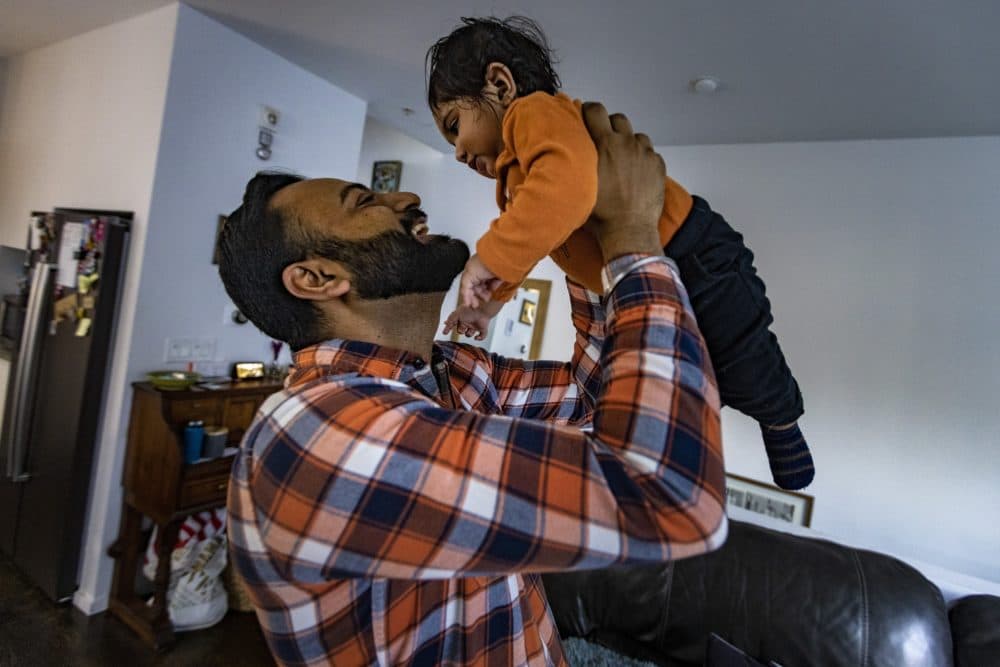 Dr. Rajandeep Singh Paik lifts his nine-month-old son Siraj after getting home from work. (Jesse Costa/WBUR)