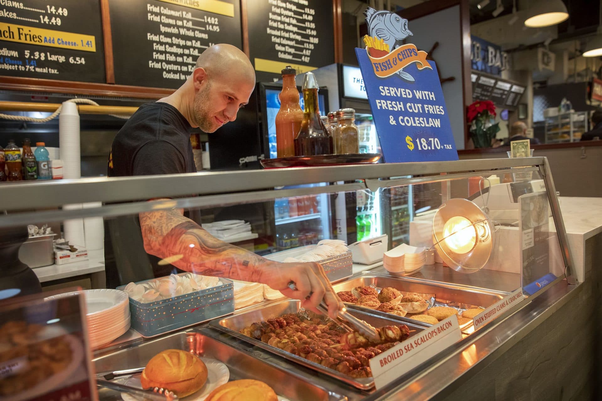 George Maherakis, owner of Fisherman's Net, arranges scallops at his storefront in Quincy Market. (Robin Lubbock/WBUR)