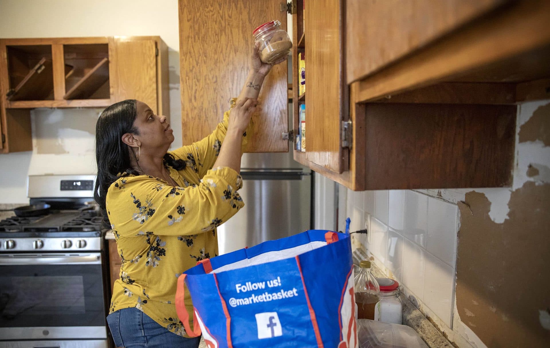 With redecorating underway at her new home in Dorchester, Cecilia Dixon unloads groceries in her kitchen. (Robin Lubbock/WBUR)